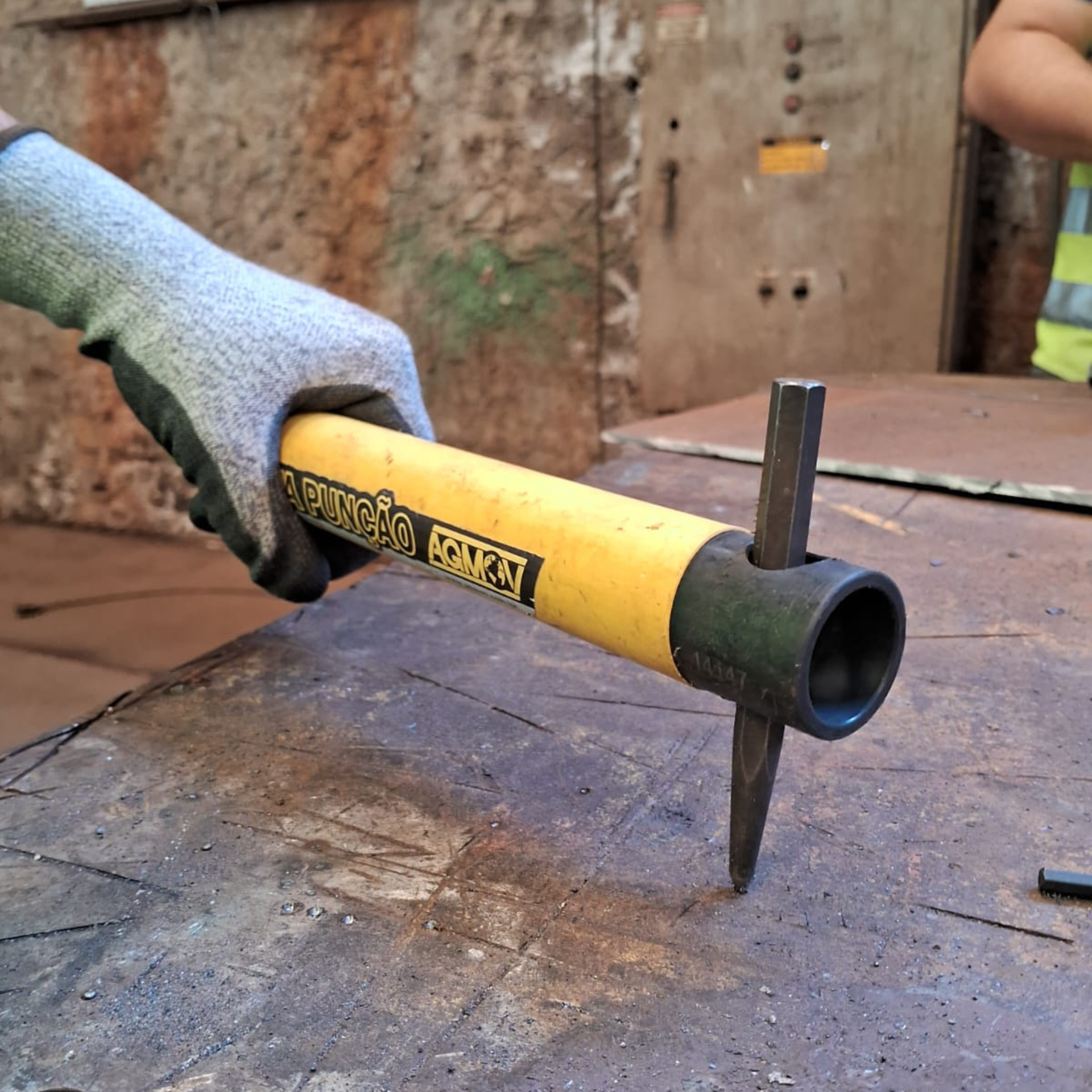 Operador utilizando o Porta-Punção AGMOV com furo de 15 mm e ímã interno para segurar punção de forma estável e segura.