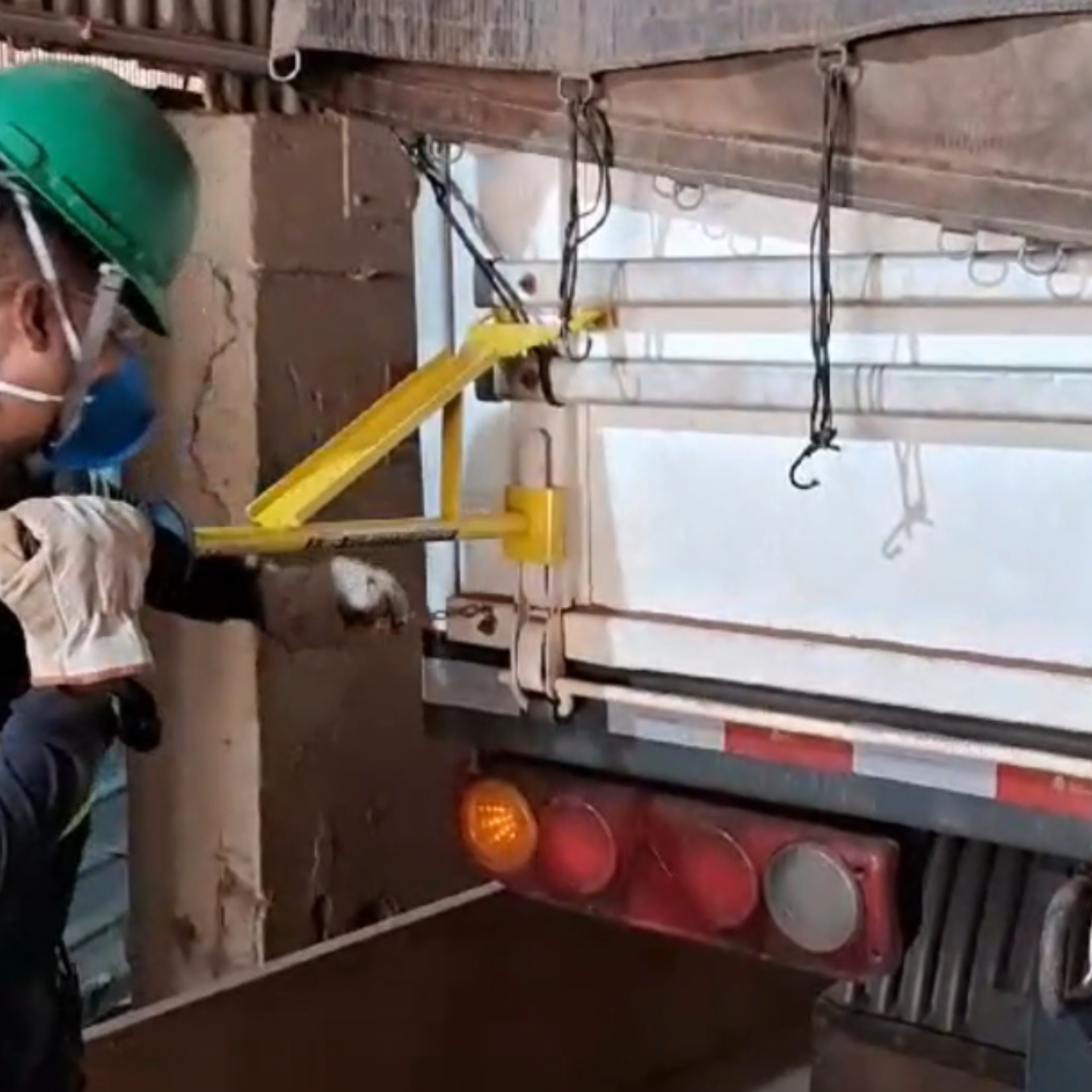 Operador utilizando o Bastão Graneleiro 3X1 para abrir e fechar tampas de caminhões graneleiros com segurança e controle.